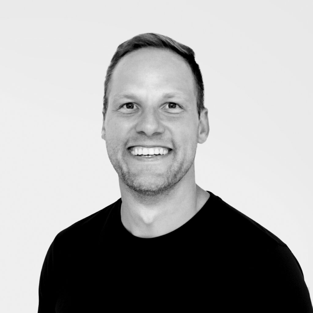 Dr. Bradley Brunner, DC (Doctor of Chiropractic), CCSP (Certified Chiropractic Sports Physician), smiling in a black shirt against a light gray background.