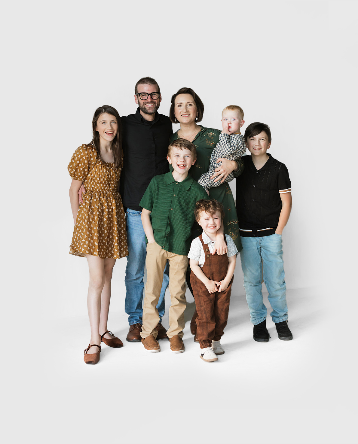 The O’Brien family poses together in a studio setting with a white background. The group includes two adults (Tim and Becki O'Brien) and five children of various ages, all smiling and dressed in coordinated, casual outfits with earthy tones.